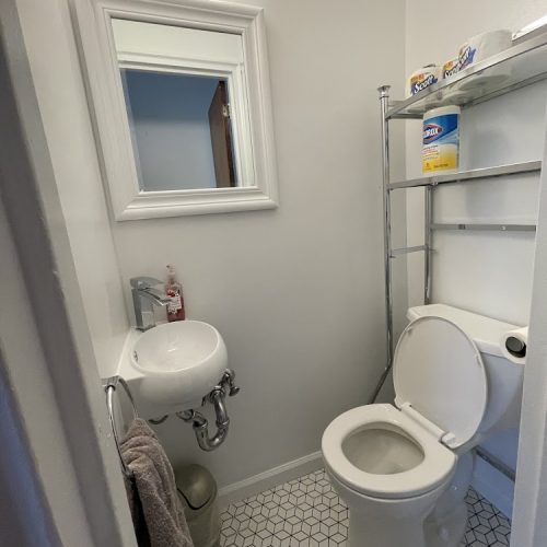 A compact bathroom featuring a toilet, sink, and mirror, designed for efficient use of space.