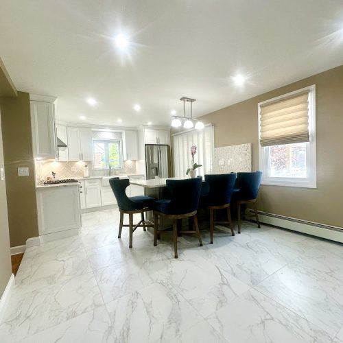 A stylish kitchen showcasing pristine marble flooring and contemporary white cabinetry, exuding a clean and airy aesthetic.