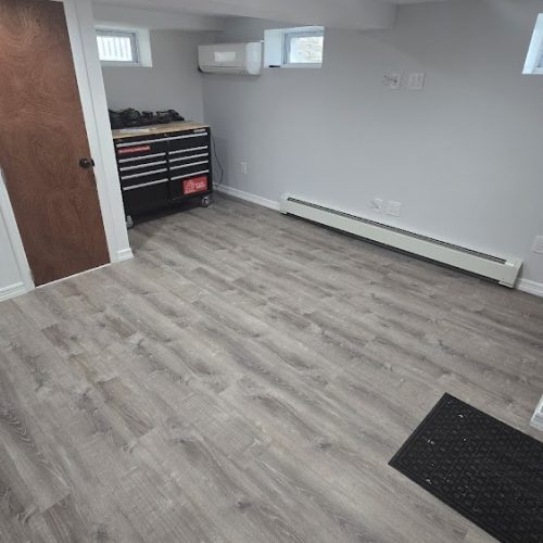 A tidy basement featuring polished wood floors and a well-organized workbench for various projects