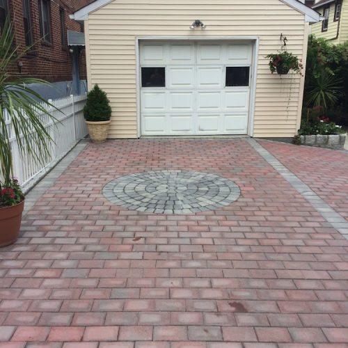 A driveway featuring brick pavers leading to a garage, showcasing a well-maintained exterior.