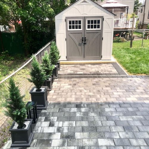 A serene backyard featuring a cozy patio and a small shed, surrounded by greenery and outdoor space.