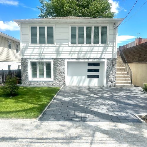 A house featuring a driveway leading to a garage, showcasing a well-maintained exterior and surrounding landscape.