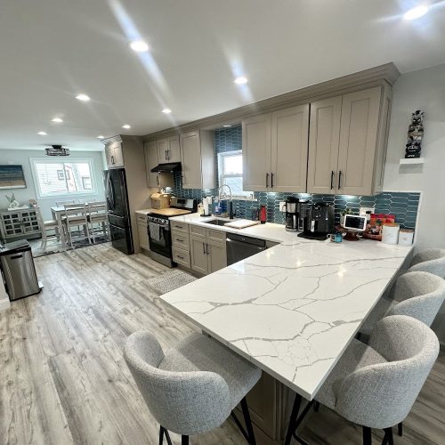 A modern kitchen featuring a white countertop and matching chairs, creating a bright and inviting atmosphere.