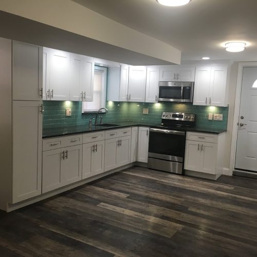 A modern kitchen featuring white cabinets and vibrant green tile, creating a fresh and inviting atmosphere.